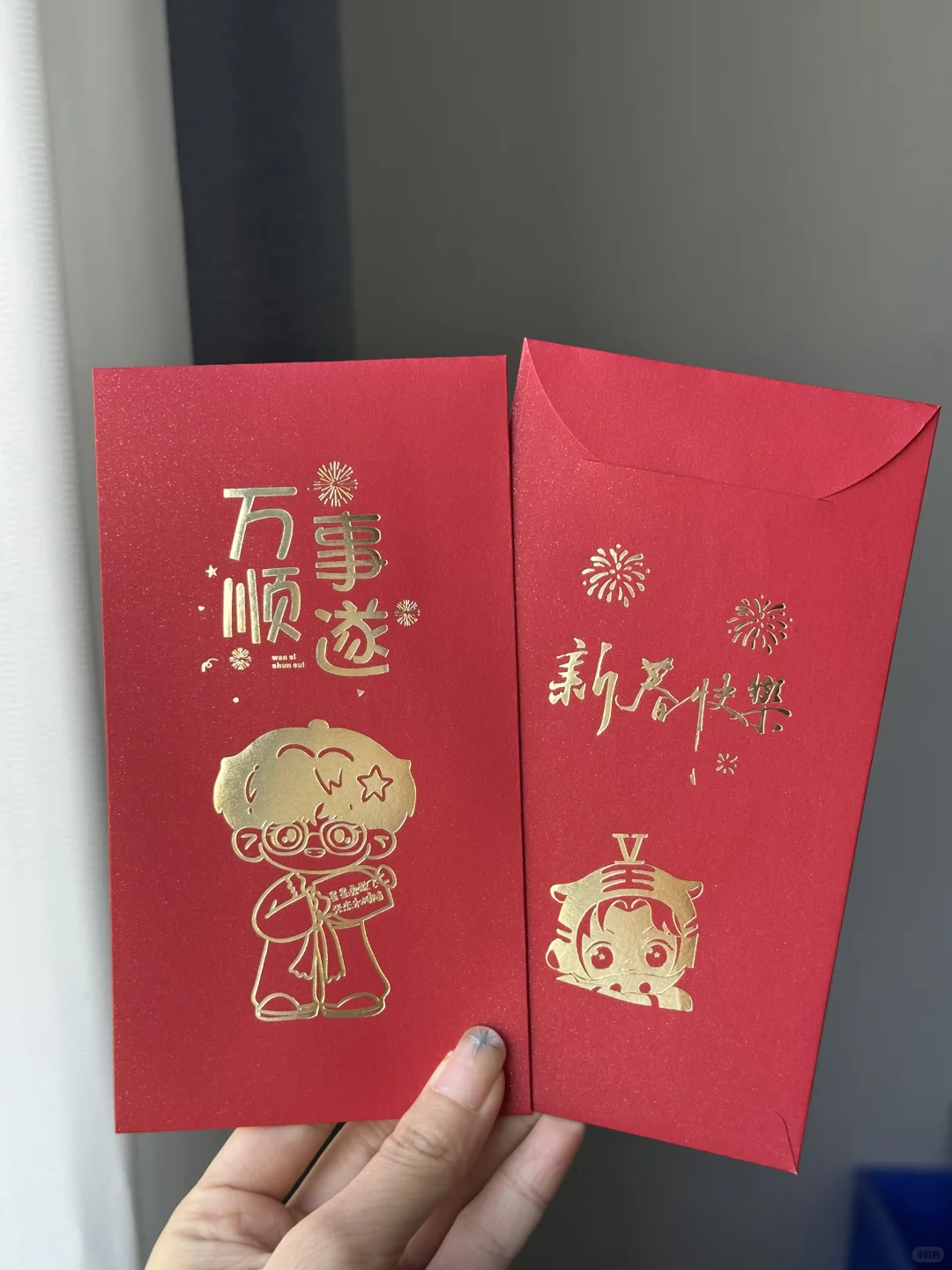 手持同款红包的正面与背面，略换拍摄角度，烫印呈金色反光。