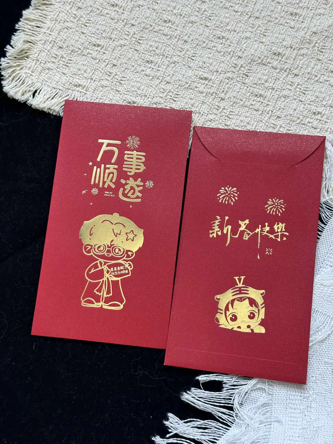 红色竖款红包在织物上并排展示正面图案与背面，封口闭合。